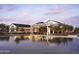 Exterior view of a lake reflecting the upscale club house with patio seating and a colorful sunset sky at 11300 N Casa Dega Dr # 1027, Surprise, AZ 85388