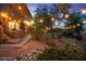 Backyard with patio, showcasing warm lighting, desert landscaping, and mature trees, perfect for outdoor evenings at 11821 S Tuzigoot Ct, Phoenix, AZ 85044