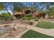 Manicured backyard featuring stone pathways, mature trees, colorful plants, and manicured artificial turf at 11821 S Tuzigoot Ct, Phoenix, AZ 85044