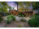 Stunning home featuring lush desert landscaping, a circular driveway, and stone accents under a colorful sunset sky at 11821 S Tuzigoot Ct, Phoenix, AZ 85044
