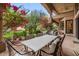 An outdoor dining area features a large table and comfortable seating surrounded by lush, colorful landscaping at 11821 S Tuzigoot Ct, Phoenix, AZ 85044