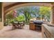 Covered patio featuring outdoor kitchen with built-in grill, sink, and dining area with comfortable seating and verdant landscaping at 11821 S Tuzigoot Ct, Phoenix, AZ 85044