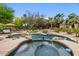 Tranquil backyard oasis features a stunning pool, jacuzzi, lush landscaping, and a comfortable lounge area for relaxation and entertainment at 11821 S Tuzigoot Ct, Phoenix, AZ 85044