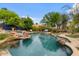 Beautiful backyard pool area with a rock waterfall feature and lush landscaping, perfect for relaxation and outdoor enjoyment at 11821 S Tuzigoot Ct, Phoenix, AZ 85044