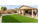 Expansive backyard showcasing lush artificial turf, play equipment, outdoor seating and mature landscaping at 12425 W Willow Ave, El Mirage, AZ 85335