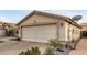 Single story tan home with a two car garage, desert landscaping, and concrete driveway at 12425 W Willow Ave, El Mirage, AZ 85335