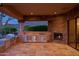 Elegant outdoor kitchen featuring stone accents, stainless steel appliances, and a cozy fireplace, perfect for entertaining at 12711 N 117Th St, Scottsdale, AZ 85259