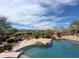 A backyard pool features a stone patio, lush landscaping, and mountain views in this desert home at 12711 N 117Th St, Scottsdale, AZ 85259