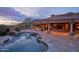 An outdoor pool and spa are surrounded by desert foliage, rocks, and a covered patio at 12711 N 117Th St, Scottsdale, AZ 85259