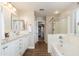 Bright bathroom featuring dual sinks, granite countertops, a soaking tub, and a separate shower with glass doors at 14095 W Larkspur Dr, Surprise, AZ 85379