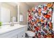 Cozy bathroom featuring a white vanity, toilet, and a shower with a floral-patterned shower curtain at 14095 W Larkspur Dr, Surprise, AZ 85379