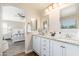 Bright bathroom featuring dual sinks, granite countertops, white cabinetry, and access to the main bedroom at 14095 W Larkspur Dr, Surprise, AZ 85379