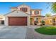 Charming two-story home with a red door garage, decorative shutters, and well-manicured landscaping at 14095 W Larkspur Dr, Surprise, AZ 85379