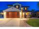 Night view of home's exterior with two-car garage, manicured lawn, and covered porch at 14095 W Larkspur Dr, Surprise, AZ 85379