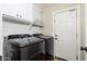 Bright laundry room features modern Samsung washer and dryer with overhead cabinets and convenient shelving at 14095 W Larkspur Dr, Surprise, AZ 85379