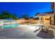 Inviting backyard featuring a refreshing pool, lounge chairs, umbrella, and a picnic table under string lights at 14095 W Larkspur Dr, Surprise, AZ 85379