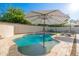 Sparkling pool with umbrellas and tanning lounges is surrounded by desert landscaping and an expansive brick patio at 14095 W Larkspur Dr, Surprise, AZ 85379