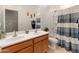 Bathroom featuring double sinks, wood cabinetry, and a shower-tub combo with a blue shower curtain at 14166 W Valentine St, Surprise, AZ 85379