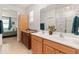 Bright bathroom featuring double sinks with tan wood cabinets and access to the primary bedroom at 14166 W Valentine St, Surprise, AZ 85379