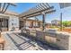 A luxurious outdoor kitchen area featuring stainless steel grills, a sink, and a stylish pergola for shade at 14166 W Valentine St, Surprise, AZ 85379