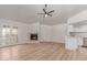 Open-concept living room with fireplace, light wood floors, and a ceiling fan blending into the updated kitchen at 16402 N 31St St # 232, Phoenix, AZ 85032