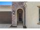 Inviting home entrance featuring an arched entryway, brick accents, a dark wood front door, and well-maintained landscaping at 16945 W Vernon Ave, Goodyear, AZ 85395