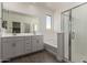 Bright bathroom with a double vanity, tub-shower combo, and glass-enclosed shower at 16996 W Fetlock Trl, Surprise, AZ 85387