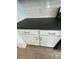 Close-up of a sleek, black countertop with white cabinets, subway tile backsplash and modern silver hardware at 16996 W Fetlock Trl, Surprise, AZ 85387