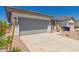 View of a two-car garage and driveway with desert rock landscaping at 16996 W Fetlock Trl, Surprise, AZ 85387