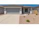 Charming single-story home featuring a gray garage door and desert landscaping at 16996 W Fetlock Trl, Surprise, AZ 85387