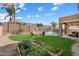 Expansive backyard with lush lawn, raised garden beds, mature landscaping, pool with safety fence, and covered patio at 18585 E Ryan Rd, Queen Creek, AZ 85142
