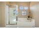 Bright bathroom features a tub with white tile surround and a glass enclosed shower at 18585 E Ryan Rd, Queen Creek, AZ 85142