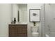 Stylish bathroom featuring wood vanity, toilet with art, and tub with shower at 23196 W Marguerite Ave, Buckeye, AZ 85326