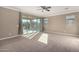 Spacious primary bedroom featuring plush carpeting, a ceiling fan, and sliding glass doors at 23789 W Chipman Rd, Buckeye, AZ 85326