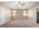 Empty main bedroom showcasing a ceiling fan, two windows, and neutral carpeting at 23789 W Chipman Rd, Buckeye, AZ 85326