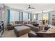 Spacious living room featuring a large sectional couch, ceiling fans, and natural light from several windows at 26049 W Matthew Dr, Buckeye, AZ 85396