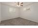 Neutral carpeted bedroom with two windows, a ceiling fan, and plantation shutters at 2808 W Lawrence Rd, Phoenix, AZ 85017