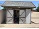 A shed with sliding barn doors and a gray roof on a brick base provides convenient backyard storage at 3514 W Altadena Ave, Phoenix, AZ 85029