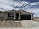 Charming single-story home featuring stone accents, a black garage door, and desert landscaping in the front yard at 46378 W Lander Ln, Maricopa, AZ 85139