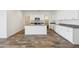 Bright kitchen showcasing white cabinetry, granite countertops, a center island, and wood-look flooring at 46378 W Lander Ln, Maricopa, AZ 85139