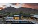 Modern home at sunset with mountain views, backyard pool, outdoor seating, and desert landscaping at 5814 E Camelback Rd, Phoenix, AZ 85018