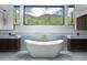 Bright bathroom with a modern soaking tub, dual vanities, and stunning mountain views from the window at 5814 E Camelback Rd, Phoenix, AZ 85018