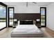 Bright bedroom featuring a king bed, wood accent wall, and two windows to view the outdoors at 5814 E Camelback Rd, Phoenix, AZ 85018