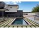 Modern backyard featuring a pool with patterned stone and grass, desert landscaping, and partial view of tennis court at 5814 E Camelback Rd, Phoenix, AZ 85018