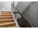 Modern wood staircase featuring glass railing and a concrete accent wall at 5814 E Camelback Rd, Phoenix, AZ 85018