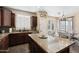 Open kitchen features granite counters, dark cabinets, and stainless steel appliances, all illuminated by natural light at 6763 W Wethersfield Rd, Peoria, AZ 85381