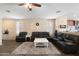Spacious living room with wood-look tile flooring, ceiling fan, and plush seating for relaxing at 6763 W Wethersfield Rd, Peoria, AZ 85381