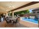 A covered patio with chairs and tables offers a beautiful view of the pristine pool and garden area at 8272 S Pecan Grove Cir, Tempe, AZ 85284