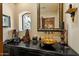 Elegant powder room with a unique sink, framed mirror, and decorative lighting at 8272 S Pecan Grove Cir, Tempe, AZ 85284