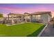 Backyard with an outdoor kitchen, lush green lawn, and a covered patio with furniture at 14640 W Dahlia Dr, Surprise, AZ 85379